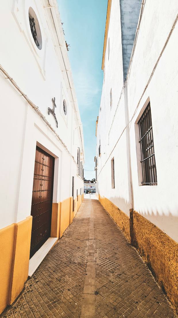 Callejón de casas blancas con zócalo amarillo